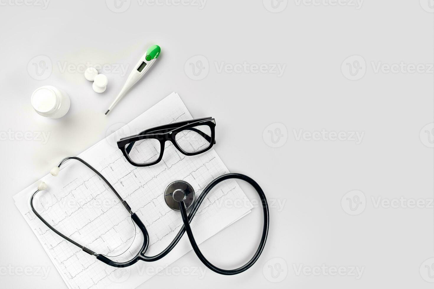 Doctor's office desk with medical documents, charts, eyeglasses and stethoscope. Top view. Copy space photo