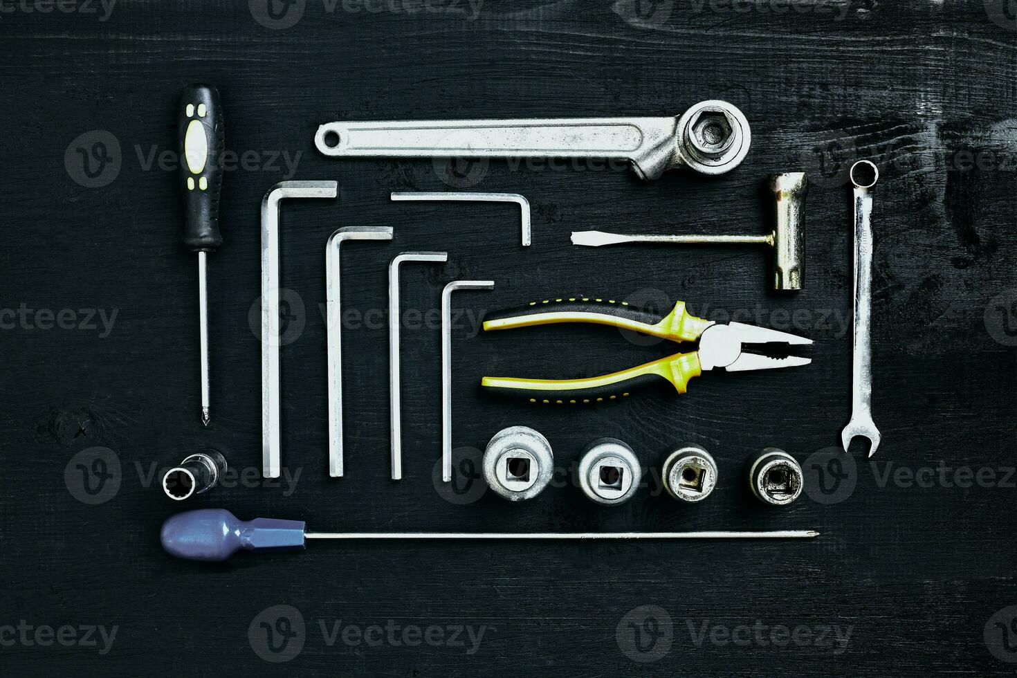 Wrench set of pliers socket spanner and screwdriver tools on black wooden background photo