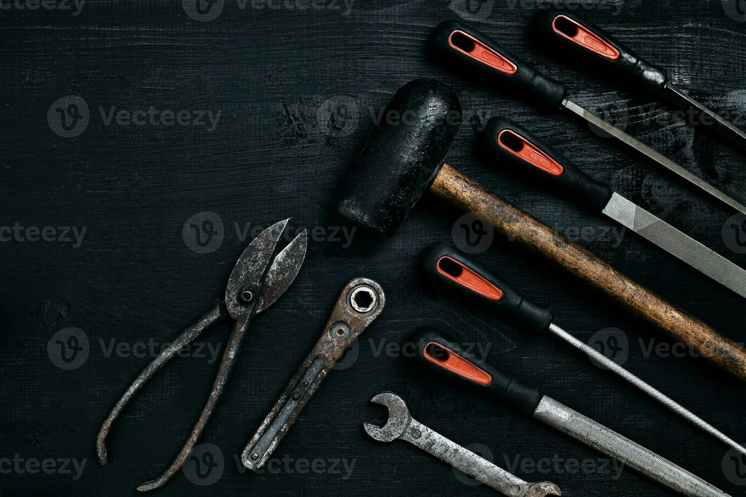 Series of many sharp steel blades and hammer on black wooden background photo