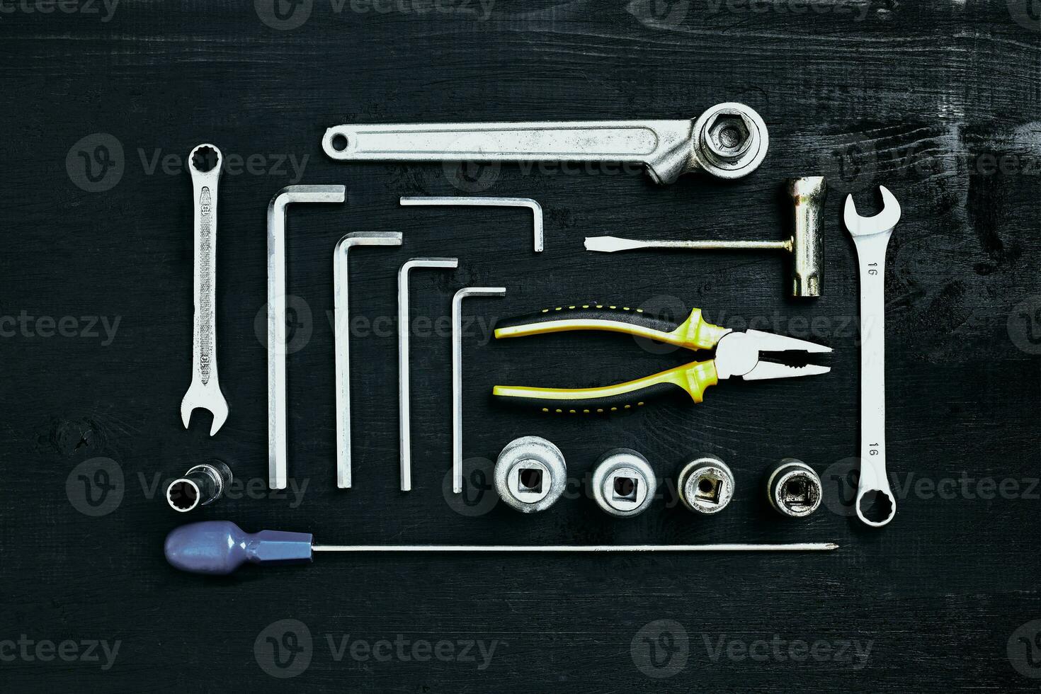 Wrench set of pliers socket spanner and screwdriver tools on black wooden background photo