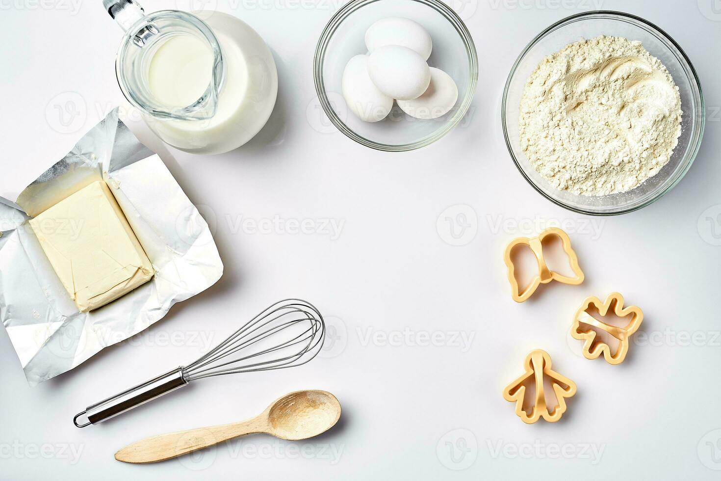 Objects and ingredients for baking, plastic molds for cookies on a white background. Flour, eggs, whisk, milk, butter, cream. Top view, space for text photo