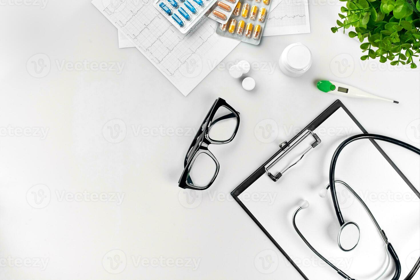 Doctor's office desk with medical documents, charts, eyeglasses and stethoscope. Top view. Copy space photo