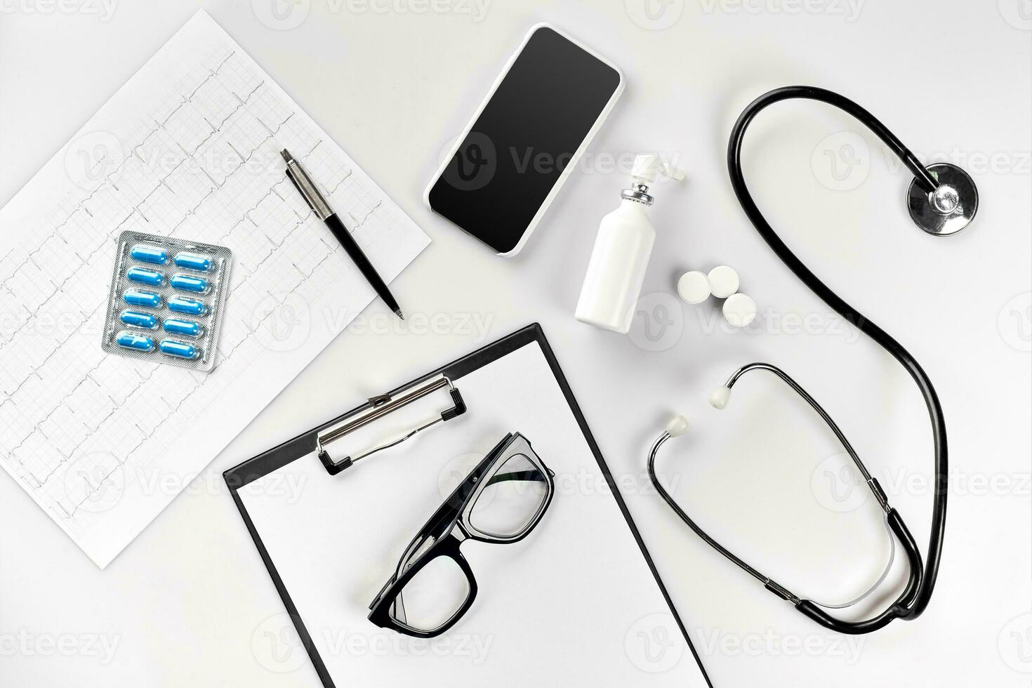 Doctor's office desk with medical documents, charts, eyeglasses and stethoscope. Top view. Copy space photo