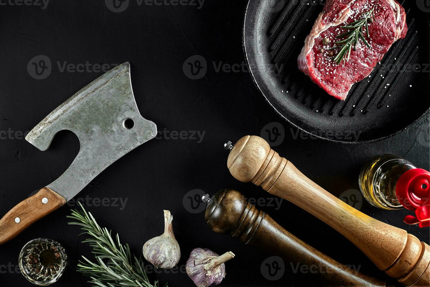 Fresh raw meat. A piece of beef tenderloin on grill pan, with a cutting ax, with spices for cooking on black stone table. Copy space photo