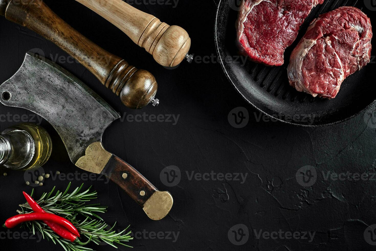 Fresh raw meat. A piece of beef tenderloin on grill pan, with a cutting ax, with spices for cooking on black stone table. Copy space photo