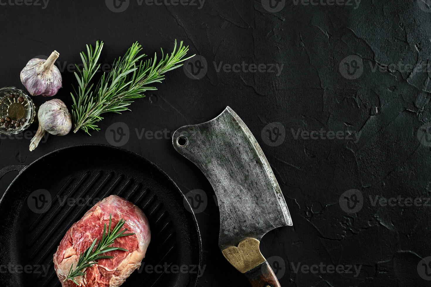 Fresh raw meat. A piece of beef tenderloin on grill pan, with a cutting ax, with spices for cooking on black stone table. Copy space photo