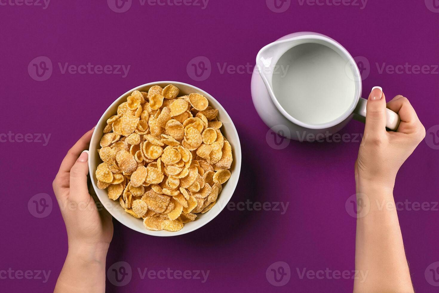 Food and people concept hands of woman eating cereals corn flakes for breakfast and pouring milk photo