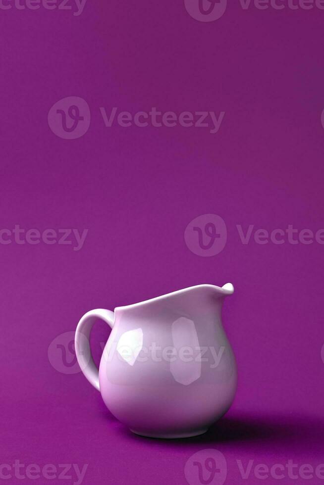 White ceramic jug of fresh milk on purple background. photo
