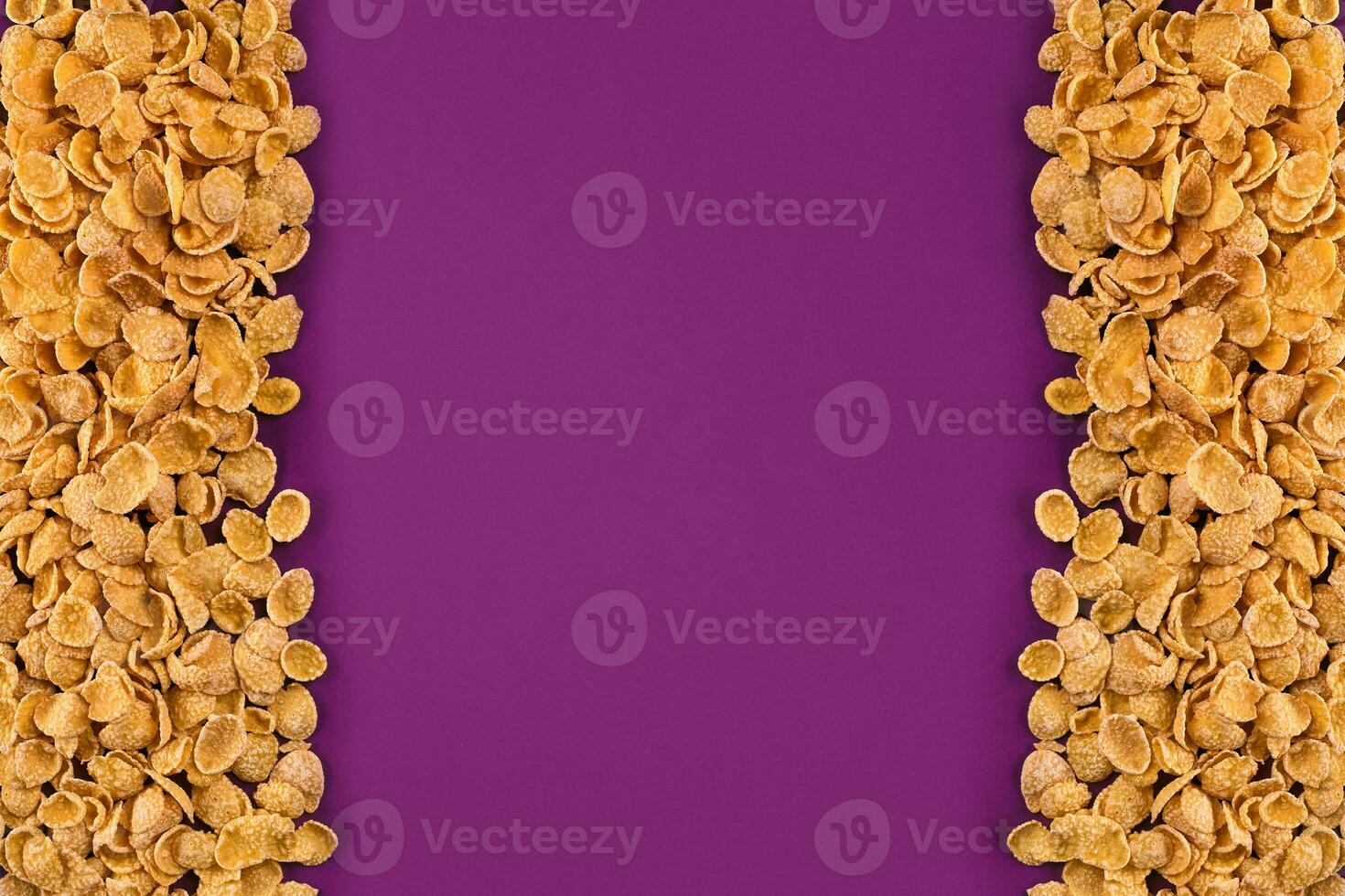 A frame lined with corn flakes. Cornflakes scattered on a purple background. Copy space photo