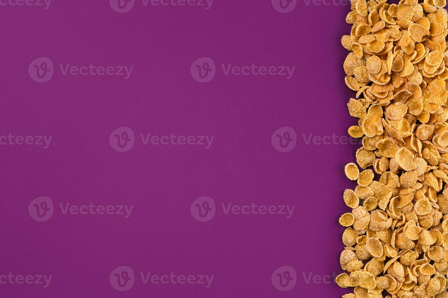 A frame lined with corn flakes. Cornflakes scattered on a purple background. Copy space photo