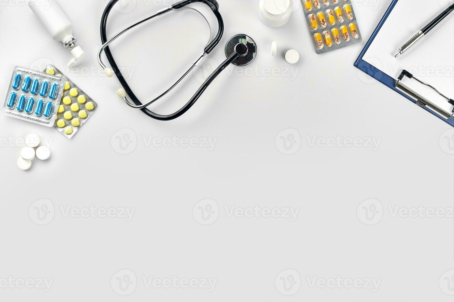 Medical equipment  pills, stethoscope and white blank with a pen on white background. Top view. Copy space photo