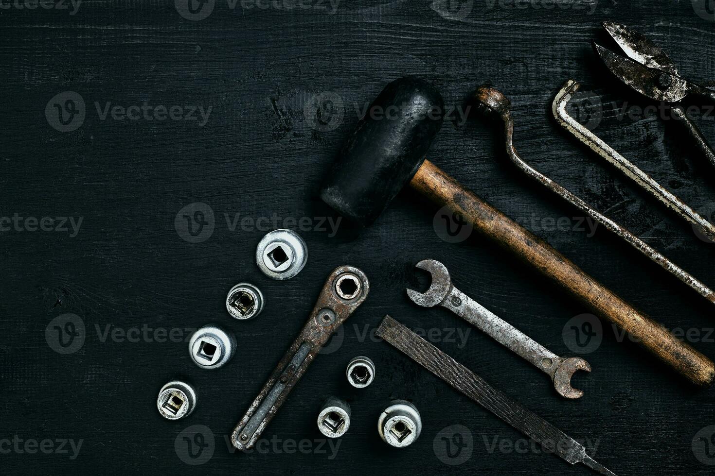 viejo, oxidado herramientas acostado en un negro de madera mesa. martillo, cincel, metal tijeras, llave inglesa. foto
