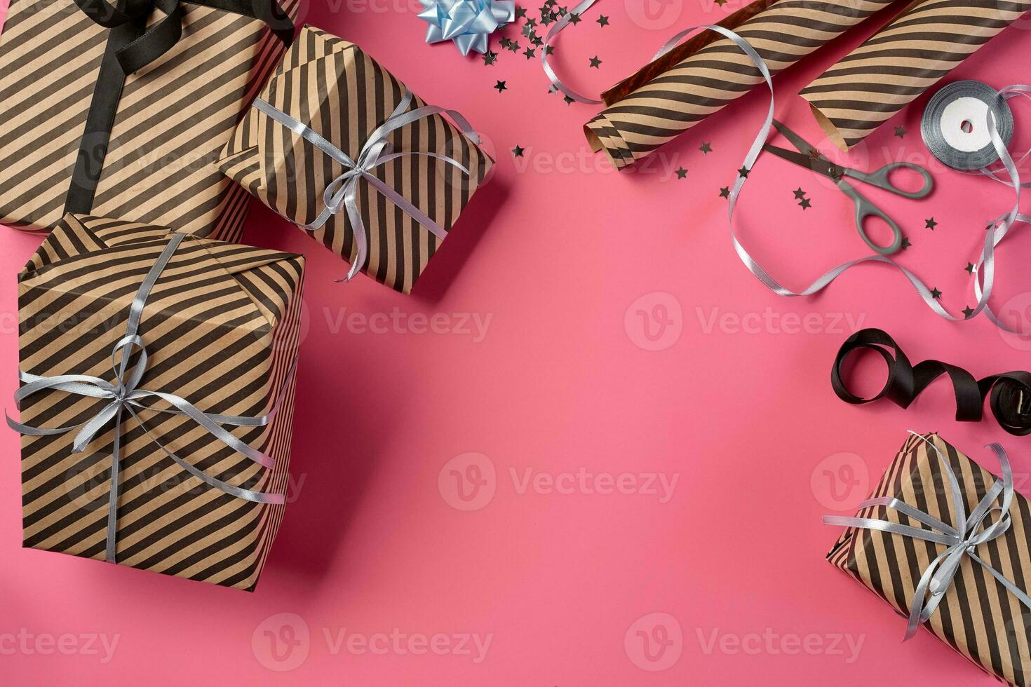 Different sizes, striped, brown gift boxes tied with black and silver ribbons and bows on a pink background. Close-up, copy space, top view. photo