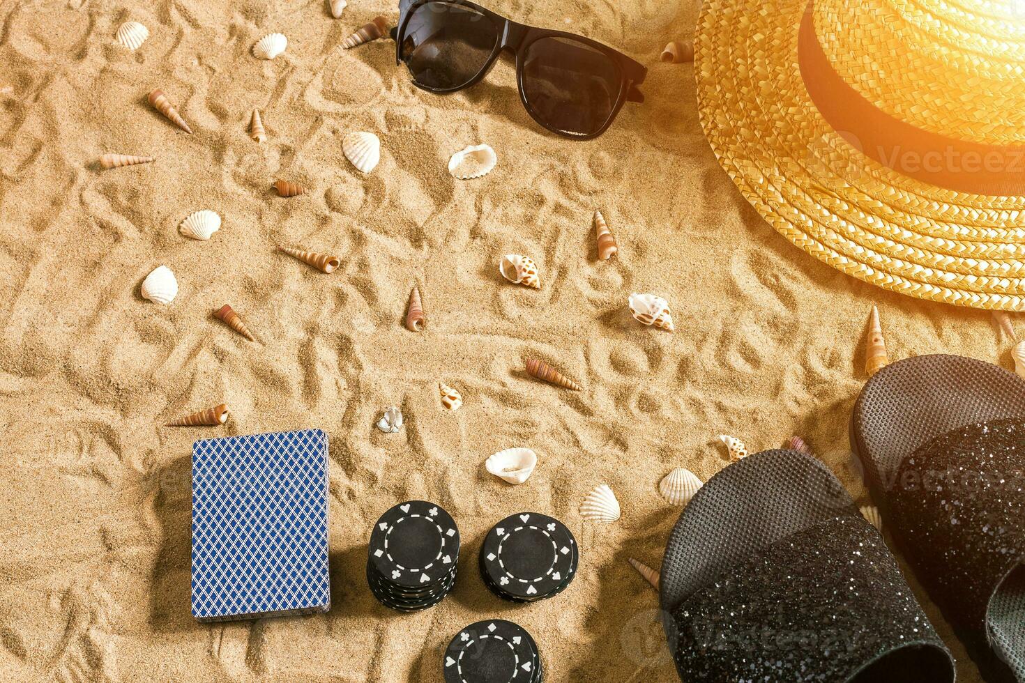 Beachpoker. Chips and cards on the sand. Around the seashells, sunglasses and flip flops. Top view photo