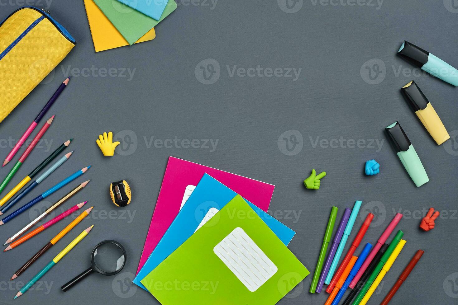 Flat lay photo of workspace desk with school accessories or office supplies on gray background.