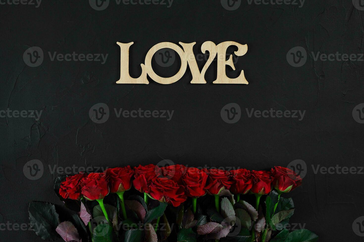 Red roses flowers with wooden word LOVE on black background with photo