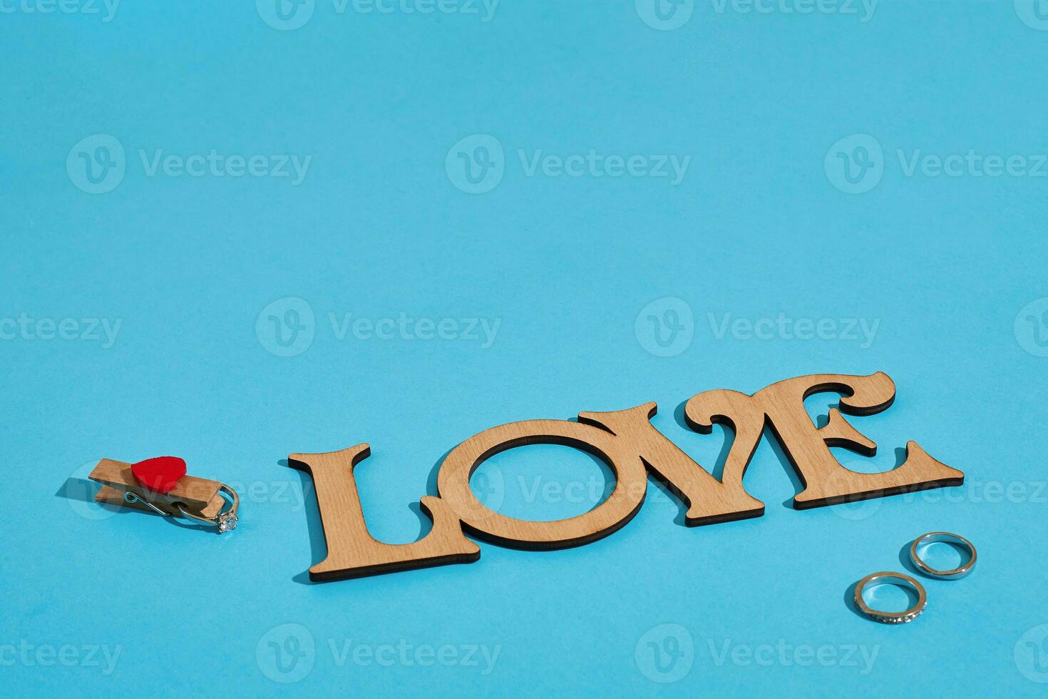 Wooden inscription Love and the ring on blue background. Marriage proposal. The concept of Valentine's Day photo