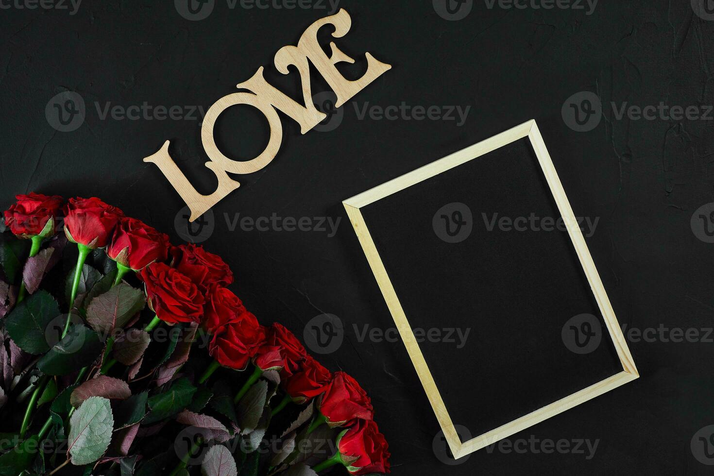 Red roses flowers with wooden word LOVE on black background with photo