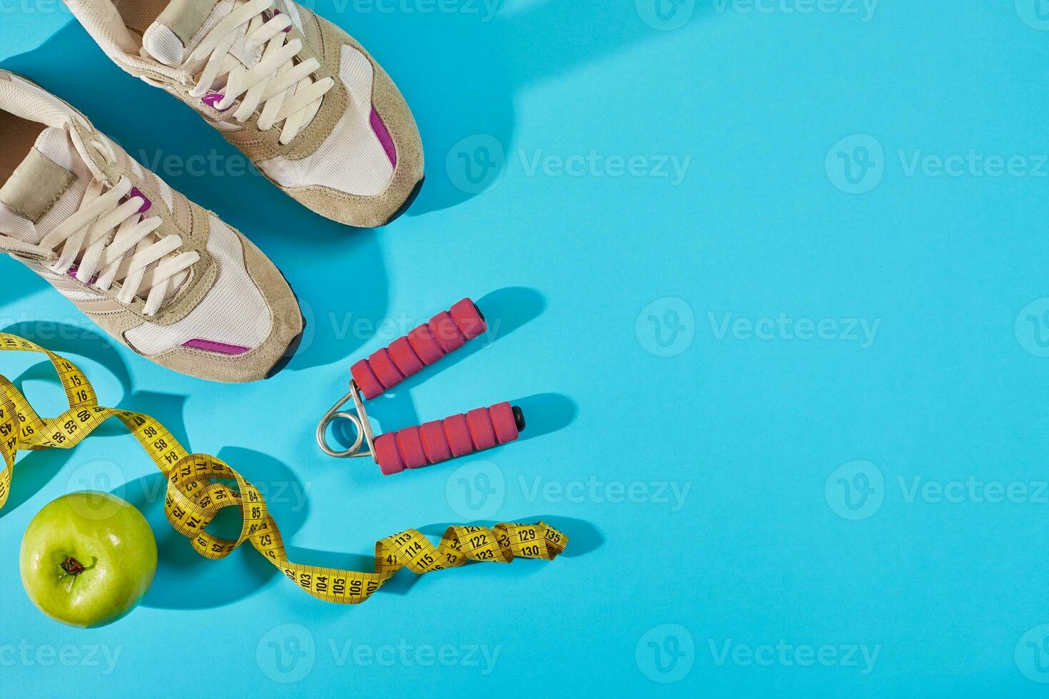 Sneakers with measuring tape on cyan blue background. Centimeter in yellow color near white trainers, close up. photo