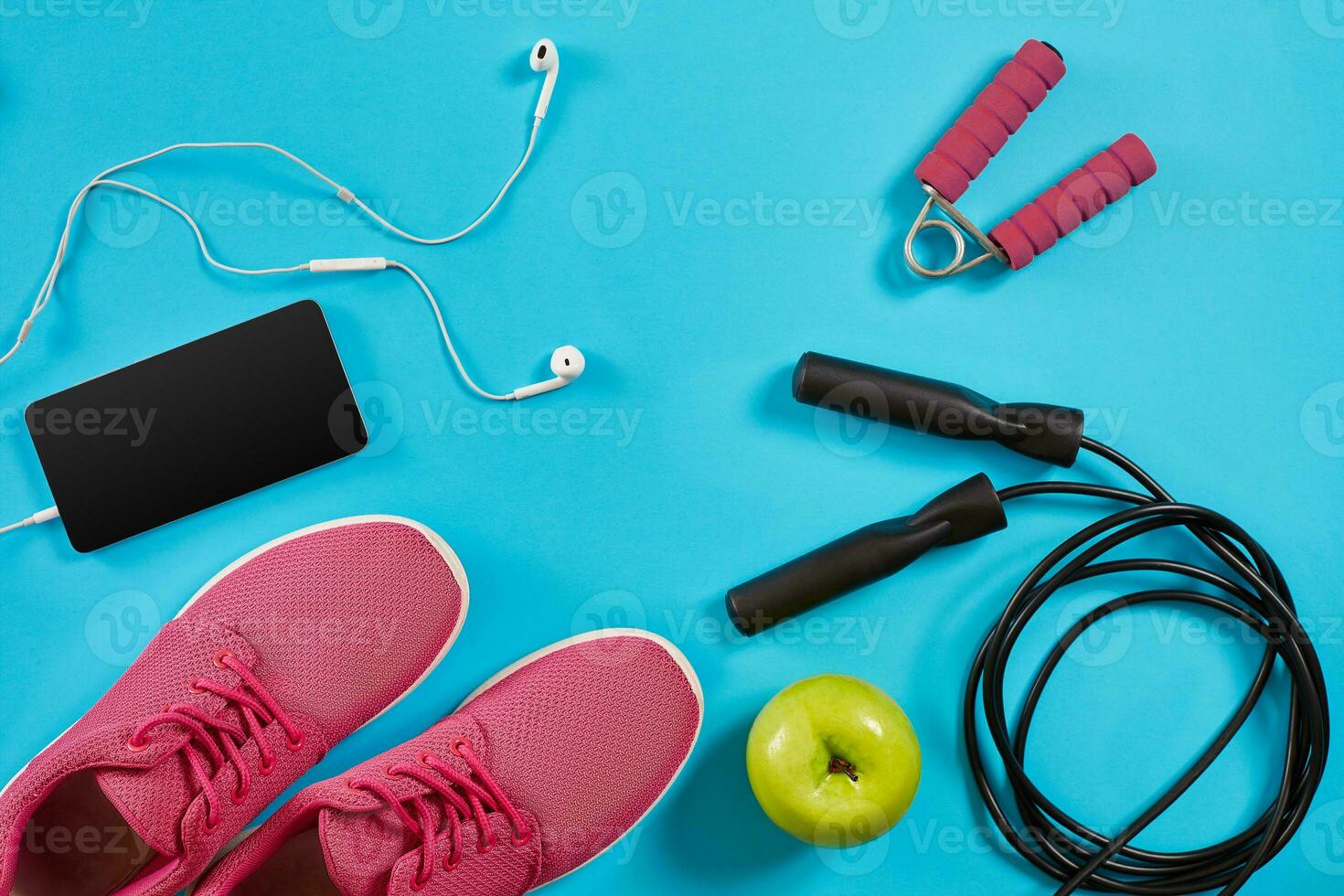 Flat lay shot of sneakers, jumping rope, dumbbells and smartphone on blue background. photo