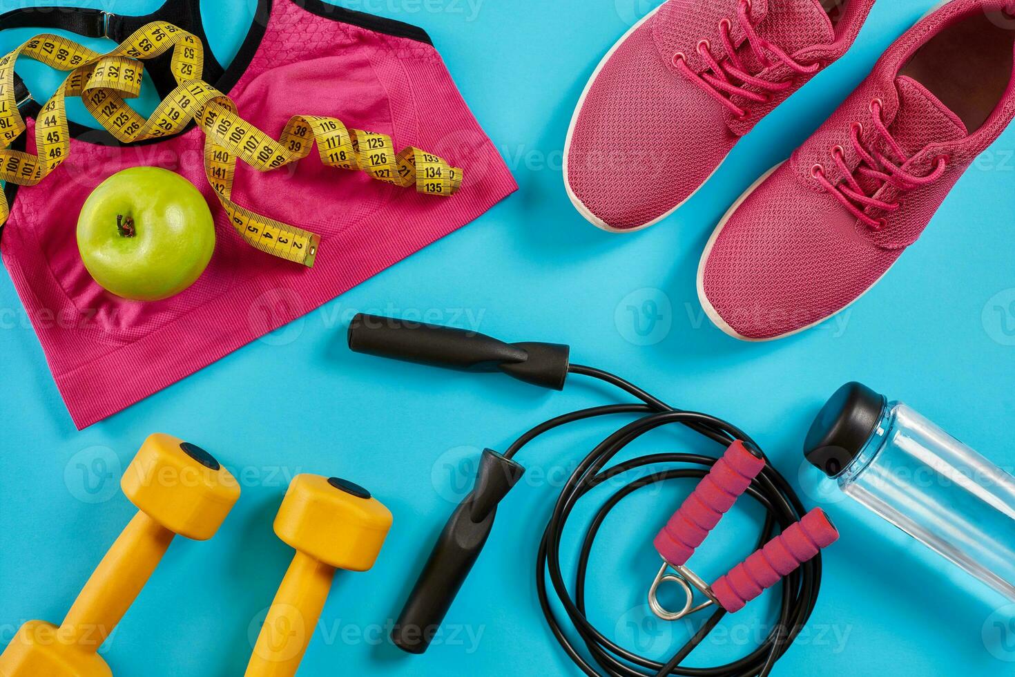 Athlete's set with female clothing, dumbbells and bottle of water on bright blue background photo