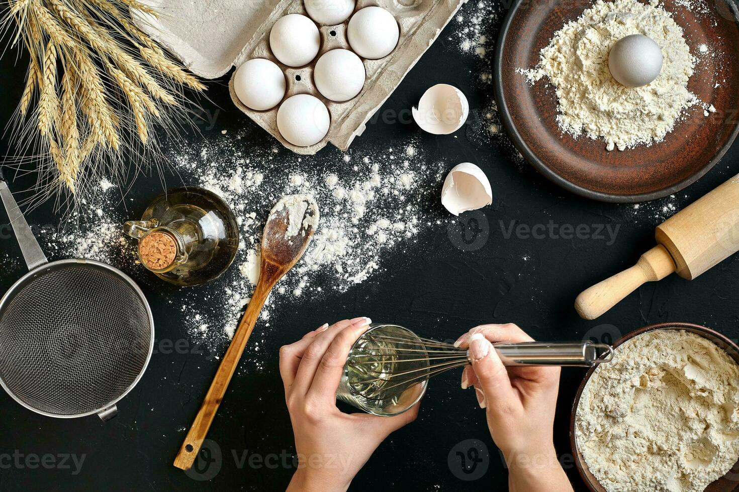 Whipping eggs. Chef hands close-up whisk eggs on a black background. View from above. photo