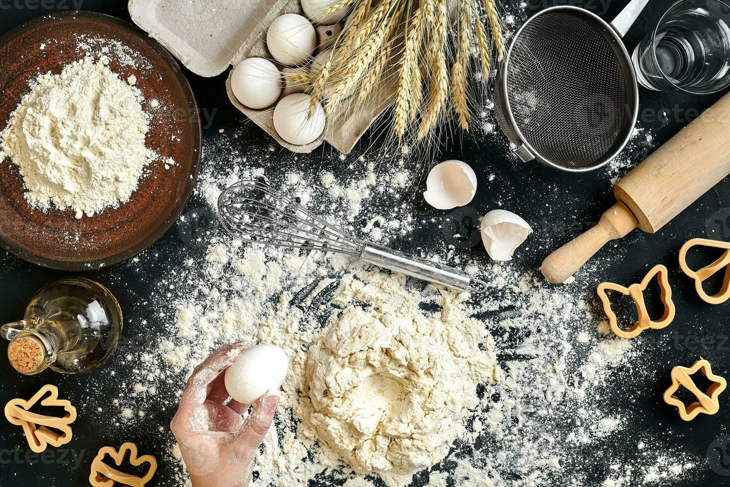 Woman smashes an egg using knife while kneading a pastry. Studio shot. Top view photo