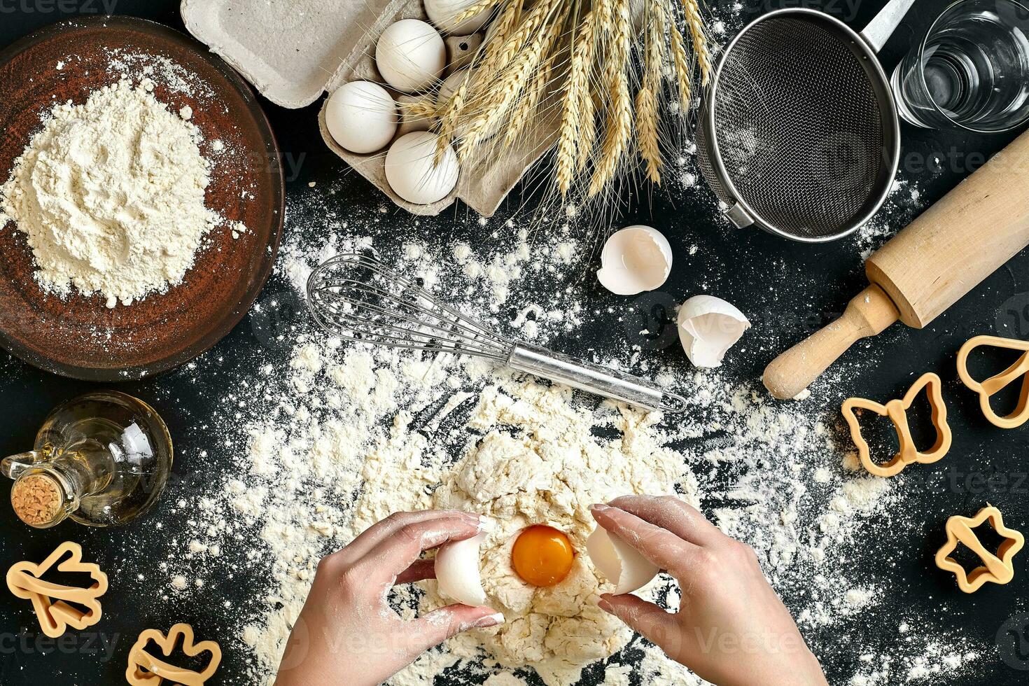 Woman smashes an egg using knife while kneading a pastry. Studio shot. Top view photo