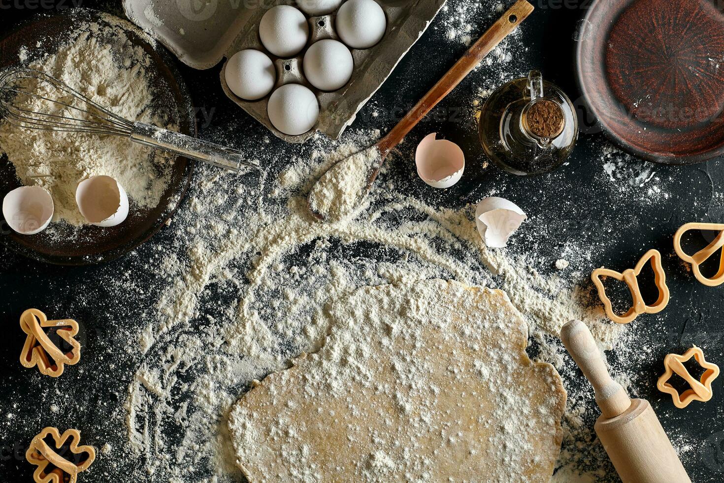 Cooking dough for cookies, butter, eggs, cooking equipment, flour on a black table. Top view with copy space, mockup for menu, recipe or culinary classes. Baking background. photo