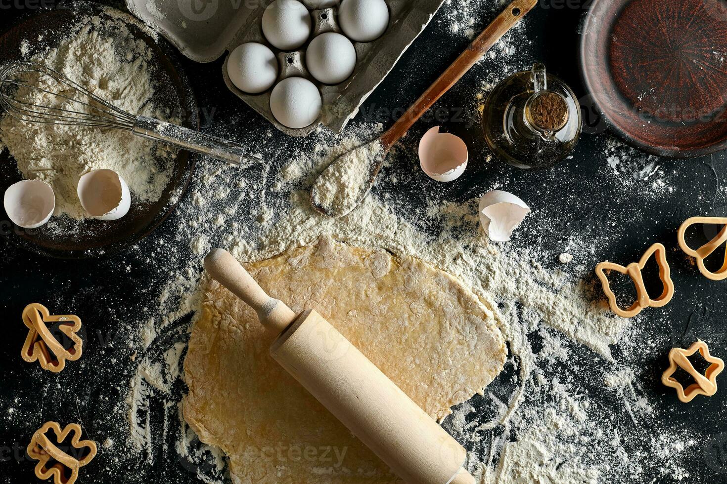 Cooking dough for cookies, butter, eggs, cooking equipment, flour on a black table. Top view with copy space, mockup for menu, recipe or culinary classes. Baking background. photo