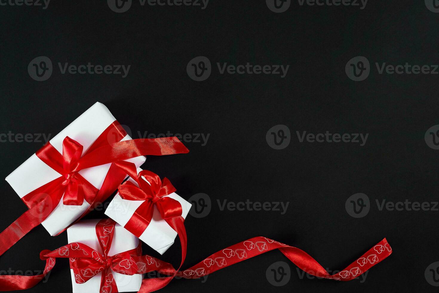 White gift boxes with red ribbon on black background. Valentines photo
