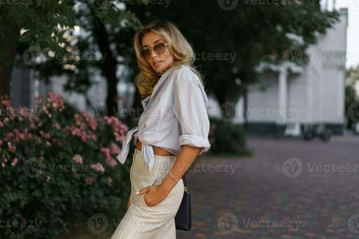 hermosa rubio mujer en elegante Moda casual atuendo posando en el calle. calentar puesta de sol color. foto