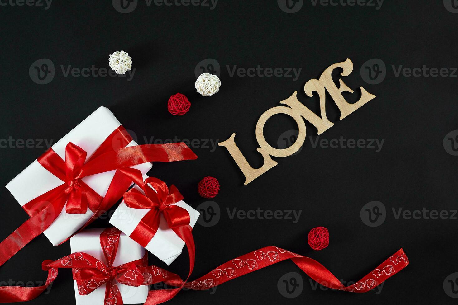 White gift boxes with red ribbon on black background. Valentines photo