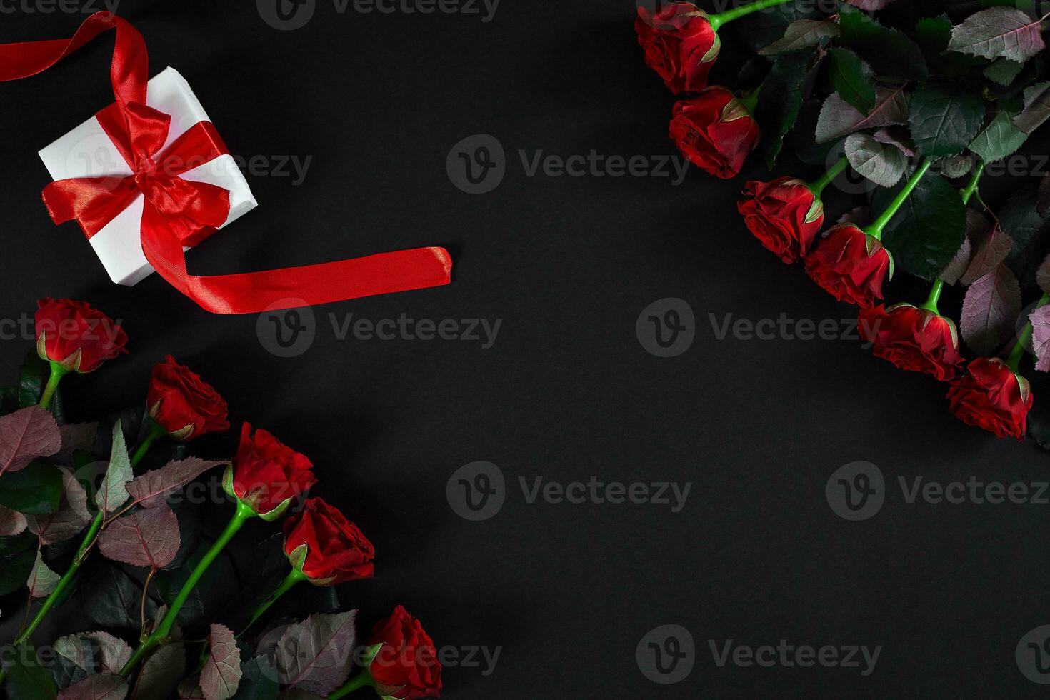 Red roses, ring and gift box on black background photo