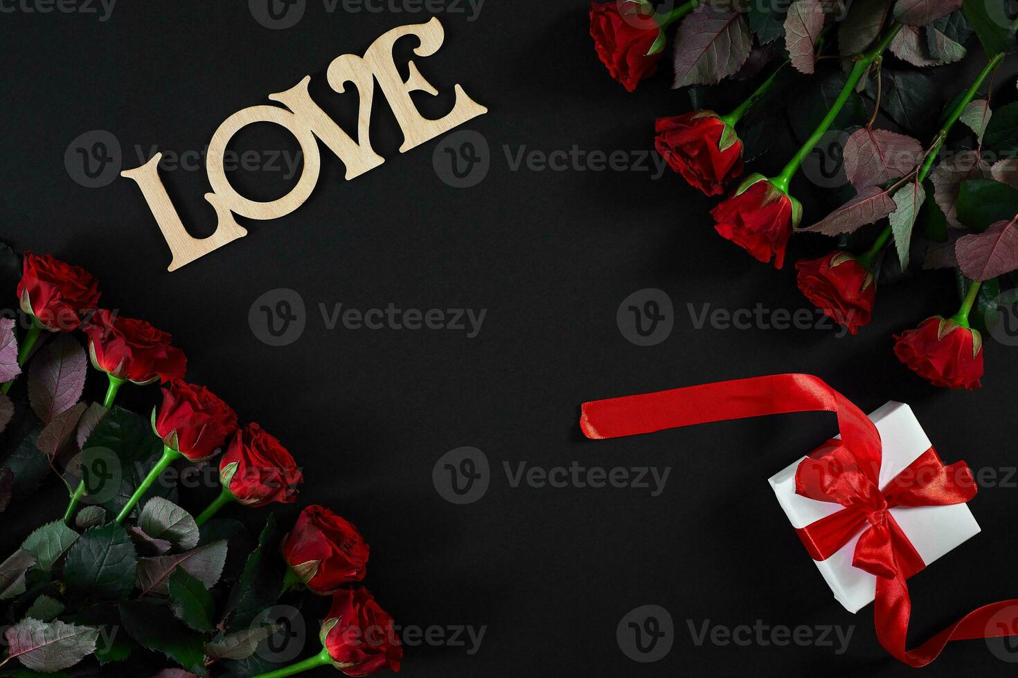 Red roses flowers with wooden word LOVE on black background with photo