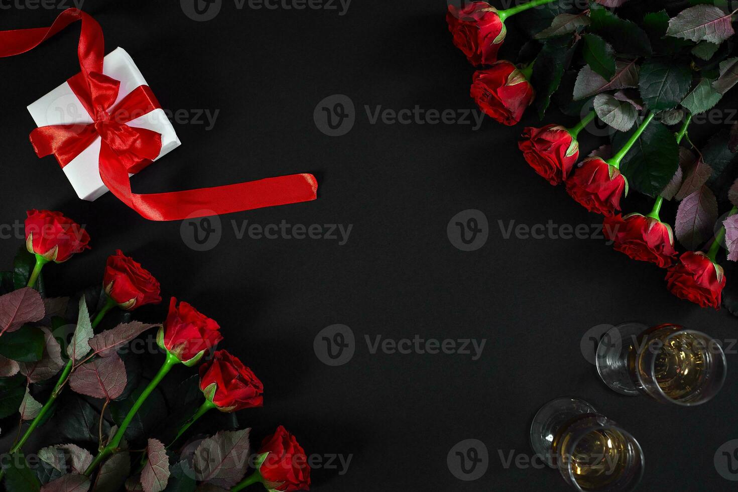 Red roses, ring and gift box on black background photo