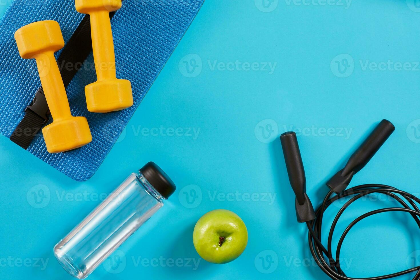 Dumbbells, bottle of water and skipping rope on blue background. Top view. Fitness, sport and healthy lifestyle concept. photo