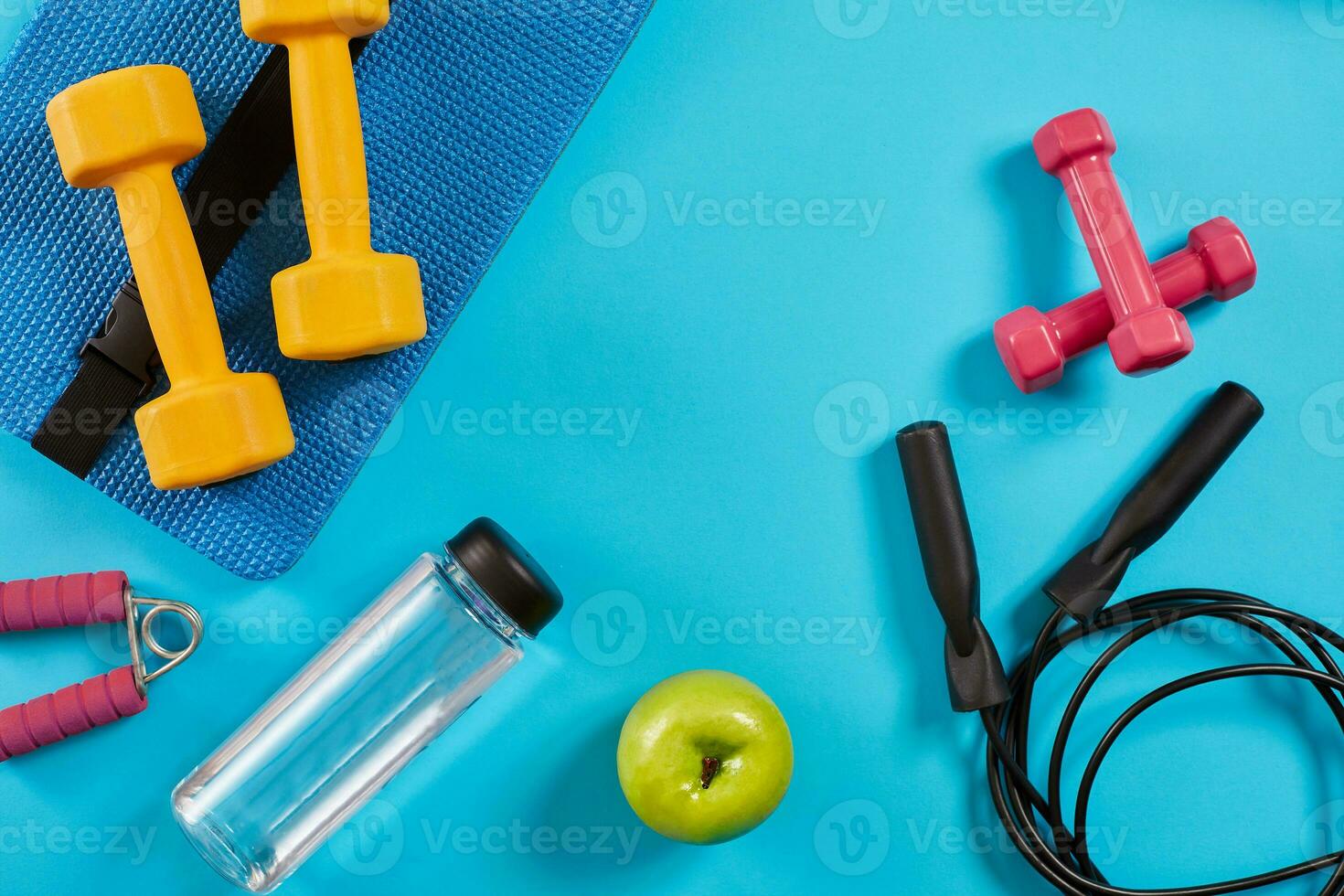 Dumbbells, bottle of water and skipping rope on blue background. Top view. Fitness, sport and healthy lifestyle concept. photo
