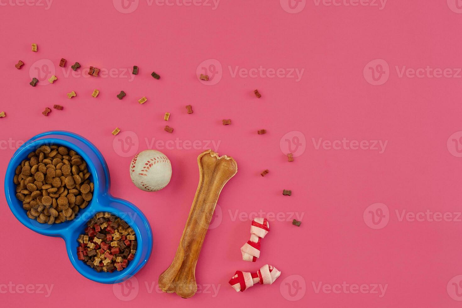Dog snacks, dog chews, dog bone, ball toy for dog on a pink background with copy space photo