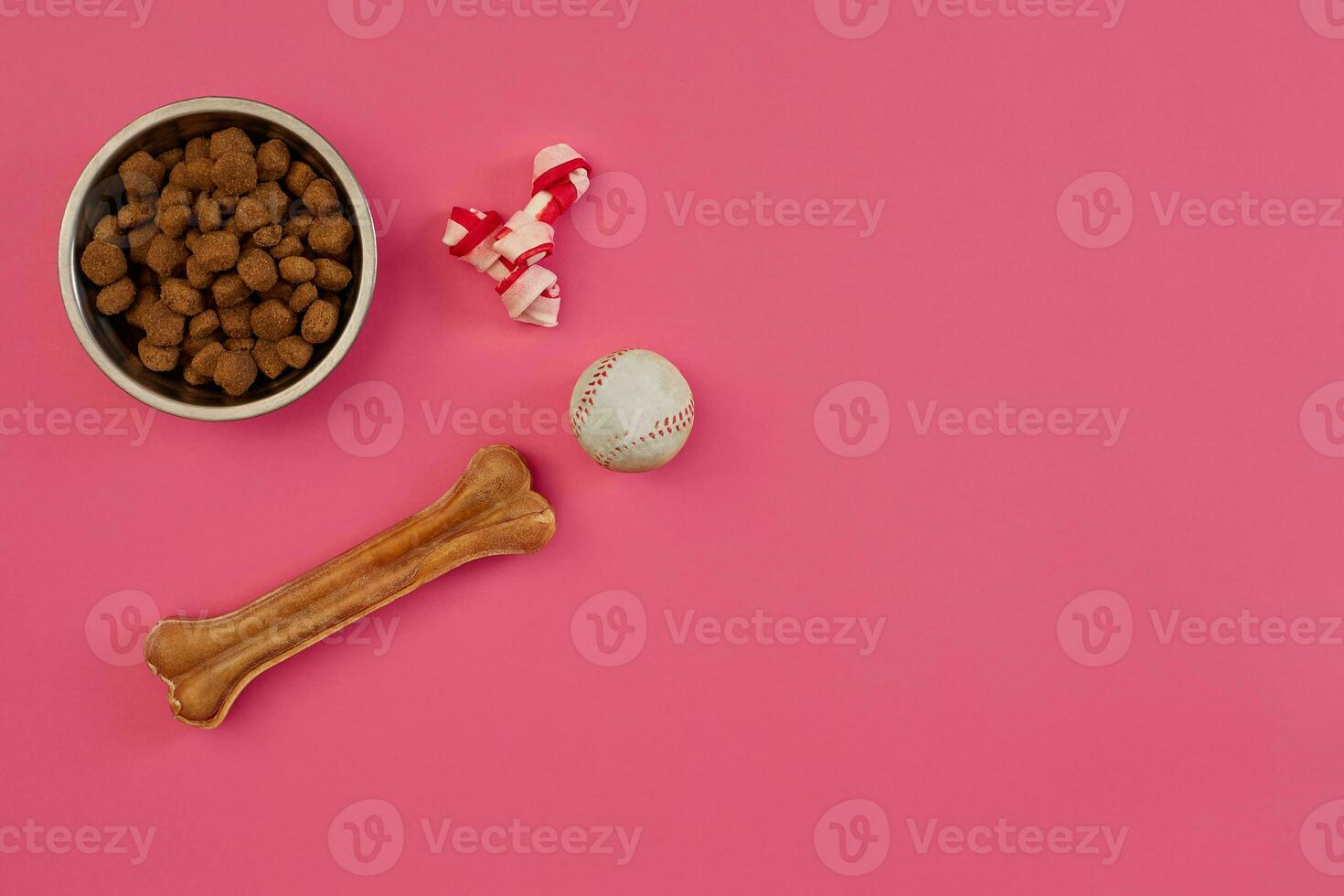 Dog snacks, dog chews, dog bone, ball toy for dog on a pink background with copy space photo