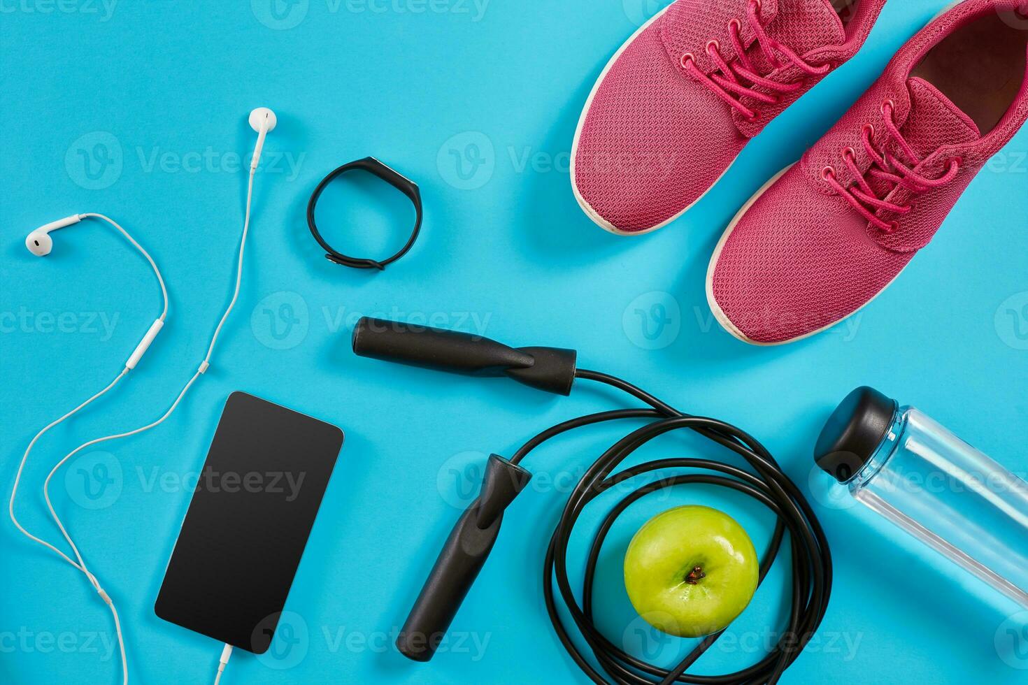 Flat lay shot of Sport equipment. Sneakers, jump rope, earphones and phone on blue background. photo
