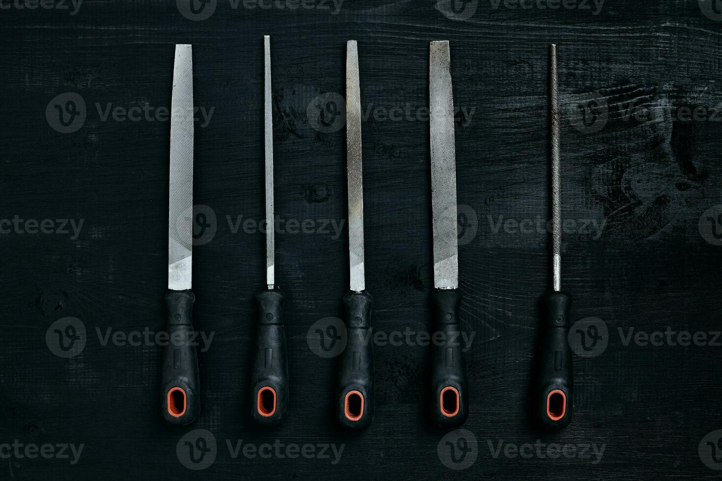 Series of many sharp steel blades on black wooden background photo