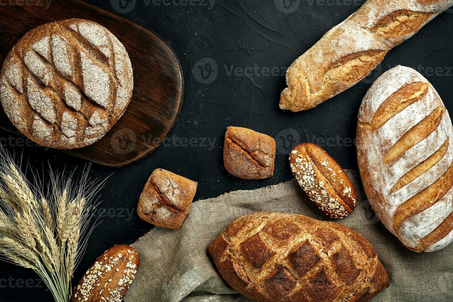 Bakery - gold rustic crusty loaves of bread and buns on black chalkboard background. photo