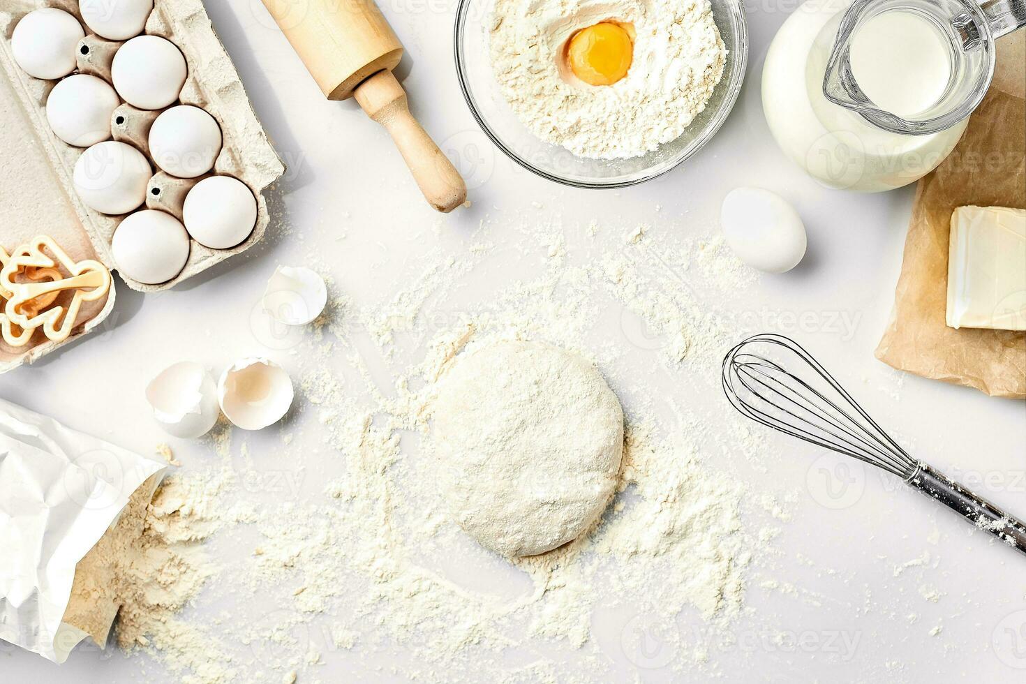 Raw dough ready for kneading on white table. Bakery ingredients, eggs, flour, butter. Shapes for making cookies. photo