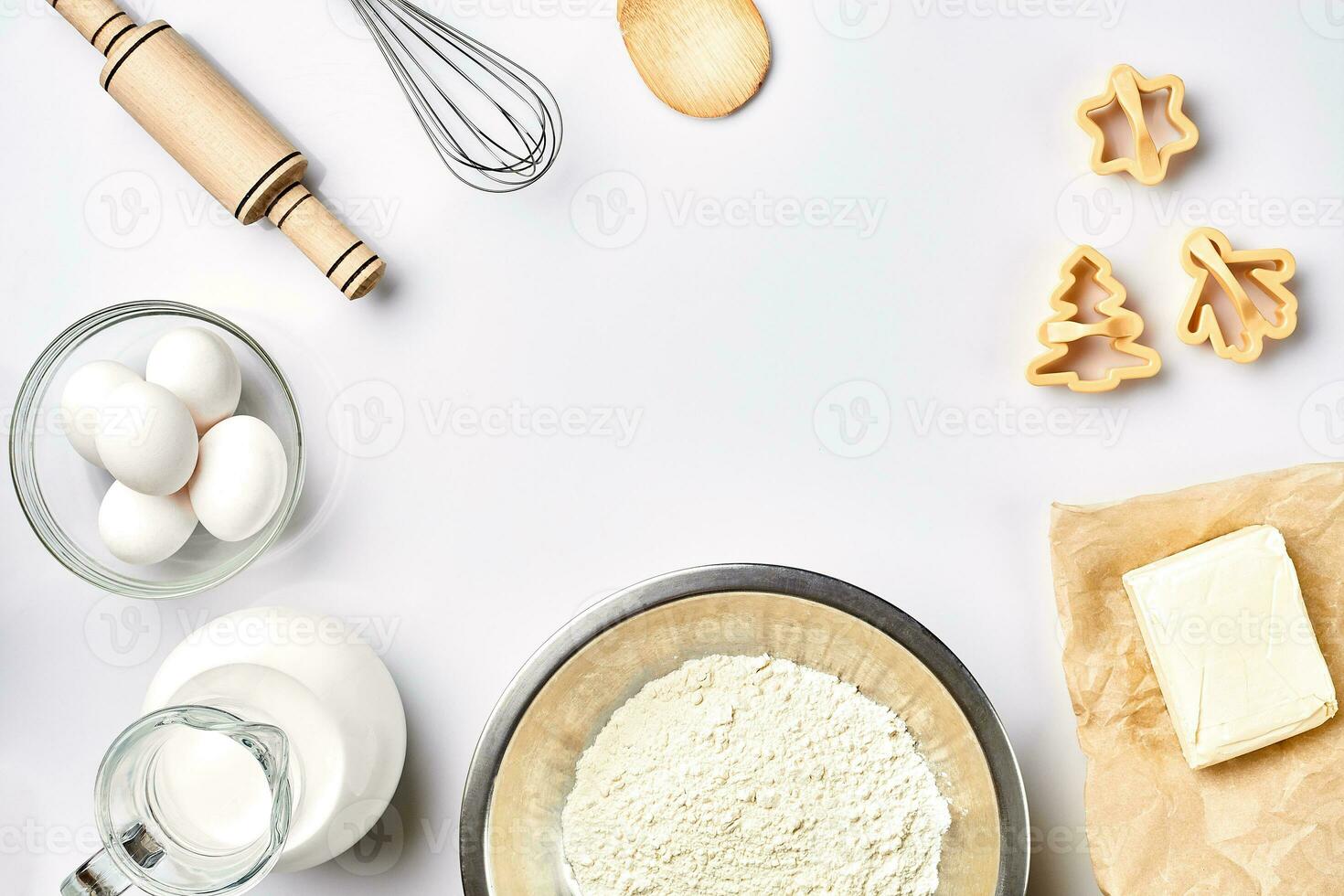 Objects and ingredients for baking, plastic molds for cookies on a white background. Flour, eggs, rolling pin, whisk, milk, butter, cream. Top view, space for text photo
