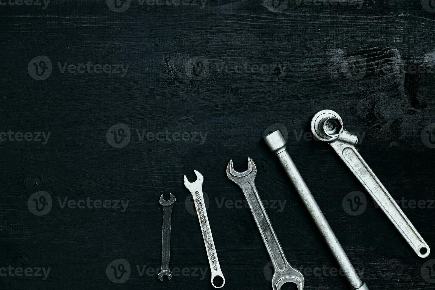 Flat lay of set of tools for car repairing such as wrenches on black wooden background. Top view. photo