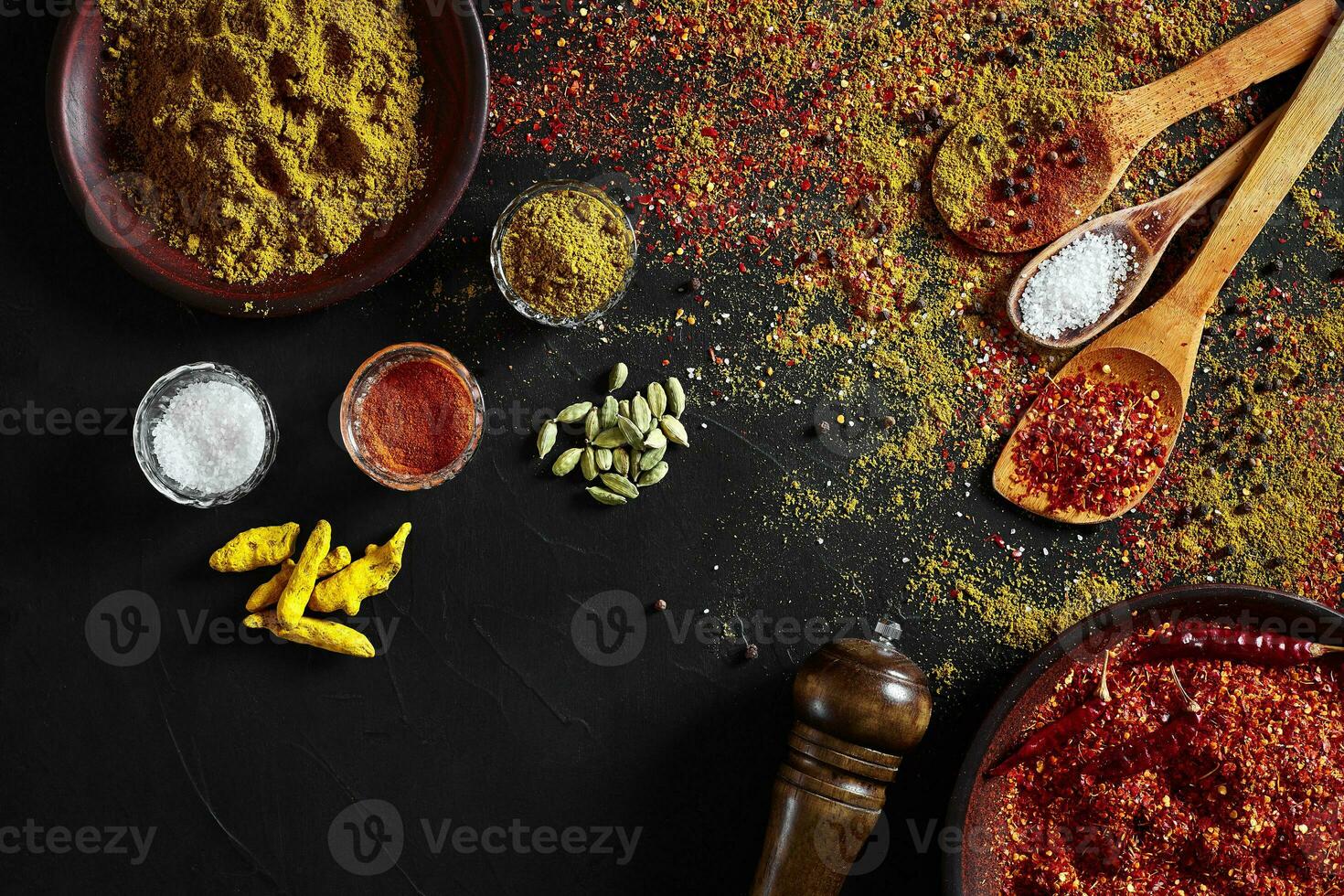 Set of indian spices on black background - green cardamom, turmeric powder, coriander seeds, cumin, and chili, top view photo