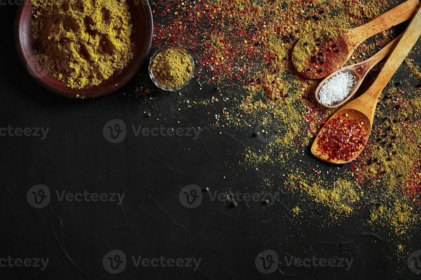 Set of indian spices on black background - green cardamom, turmeric powder, coriander seeds, cumin, and chili, top view photo