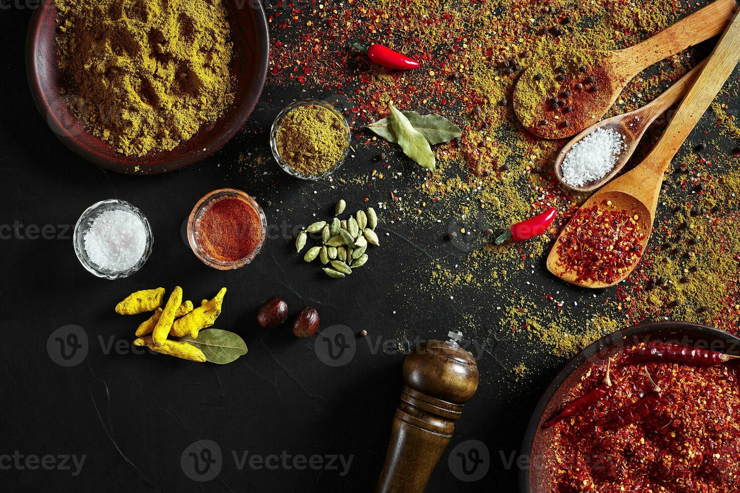 Set of indian spices on black background - green cardamom, turmeric powder, coriander seeds, cumin, and chili, top view photo