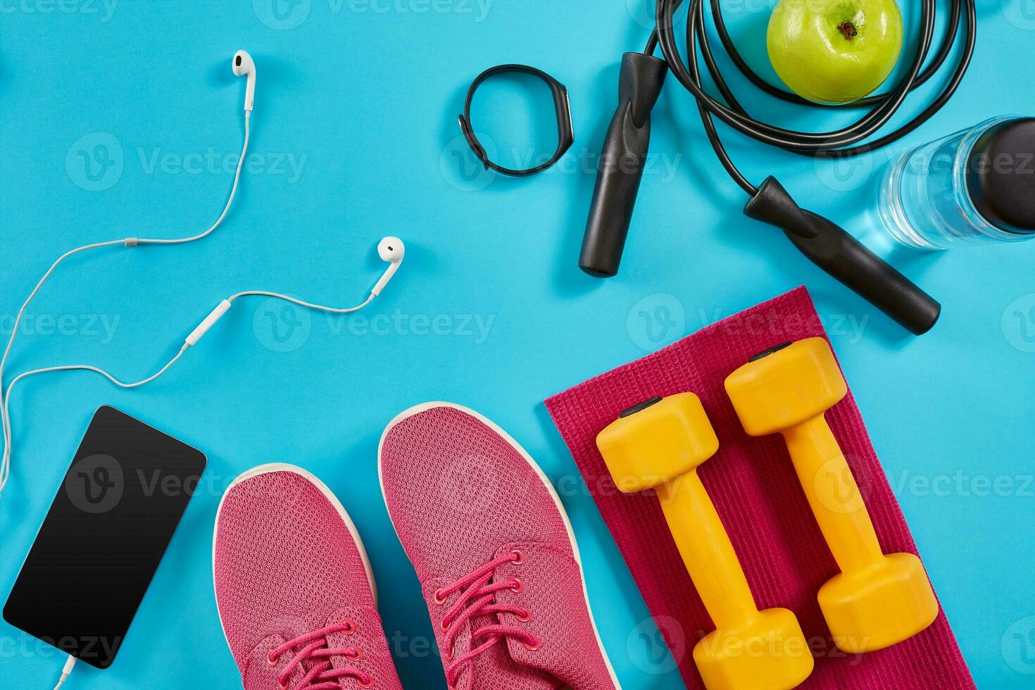 Flat lay shot of sneakers, jumping rope, dumbbells and smartphone on blue background. photo